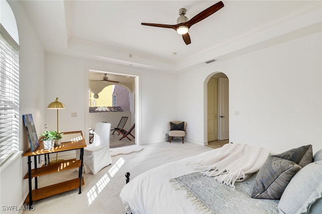 carpeted bedroom featuring a tray ceiling and ceiling fan