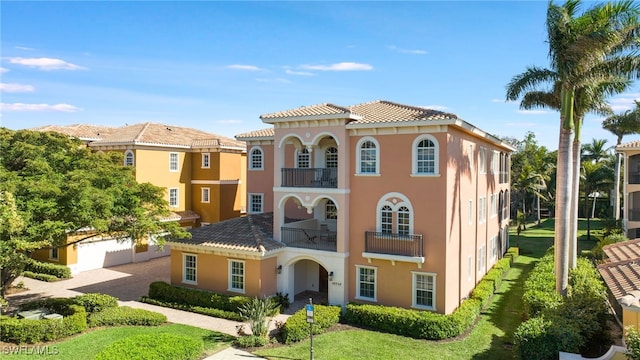 mediterranean / spanish-style house featuring a front yard and a balcony