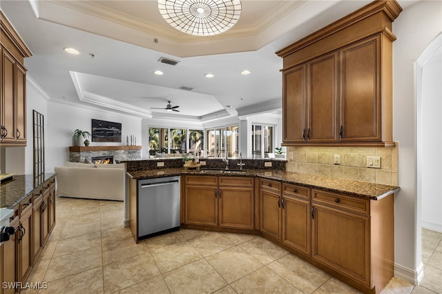 kitchen featuring dishwasher, a raised ceiling, crown molding, and dark stone counters