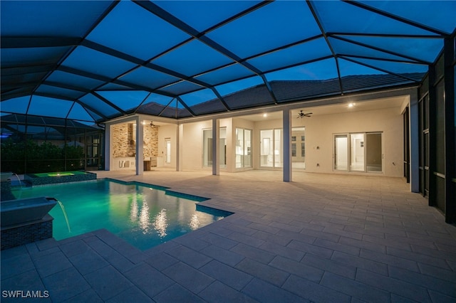 view of swimming pool featuring a pool with connected hot tub, glass enclosure, a patio area, and a ceiling fan