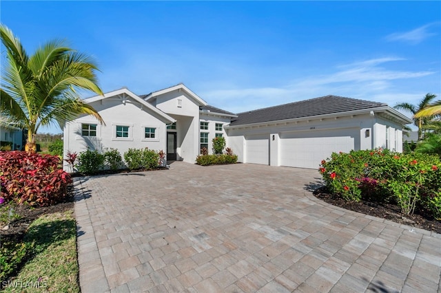 single story home with decorative driveway, an attached garage, and stucco siding