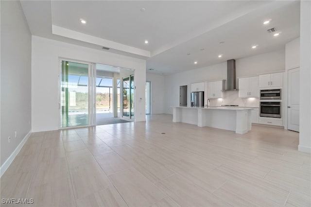 unfurnished living room with a raised ceiling and sink