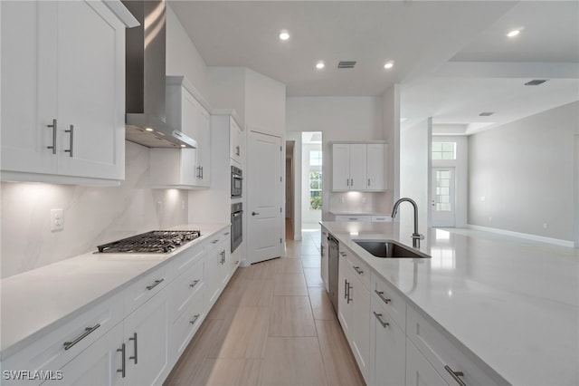 kitchen featuring white cabinets, appliances with stainless steel finishes, sink, and wall chimney range hood