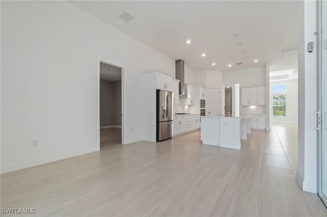 kitchen featuring stainless steel fridge with ice dispenser, a center island with sink, white cabinetry, and wall chimney exhaust hood