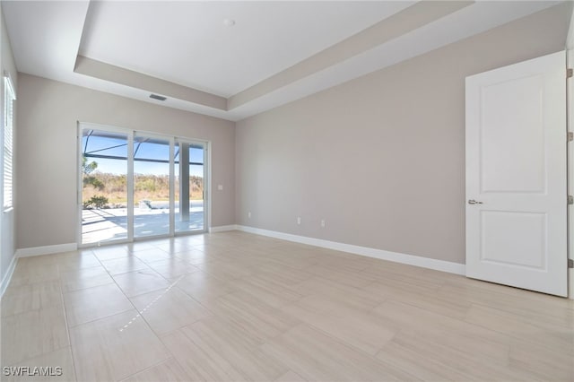 spare room featuring a tray ceiling and light tile patterned flooring