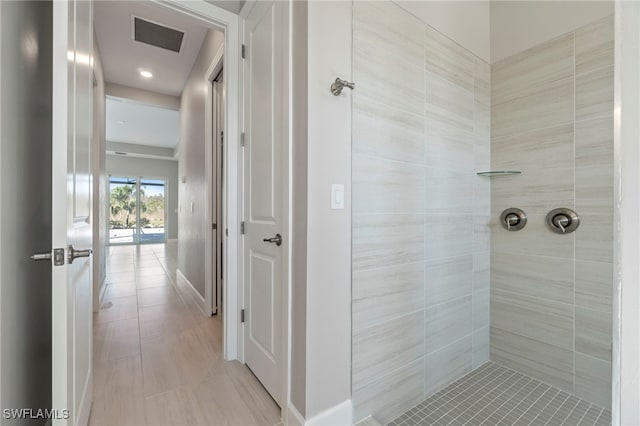 bathroom with a tile shower and tile patterned flooring