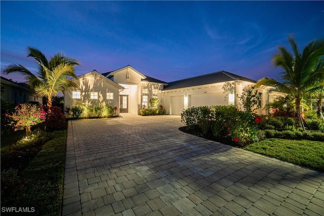 view of front of property with an attached garage, decorative driveway, and stucco siding