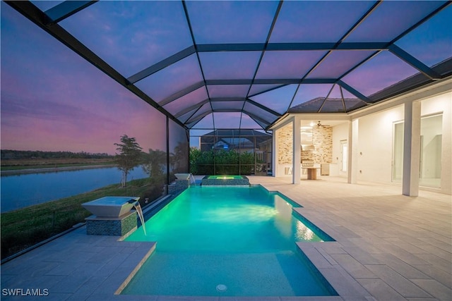 pool at dusk featuring pool water feature, a water view, a patio area, and a lanai