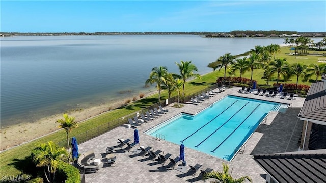 pool with a patio area, fence, and a water view