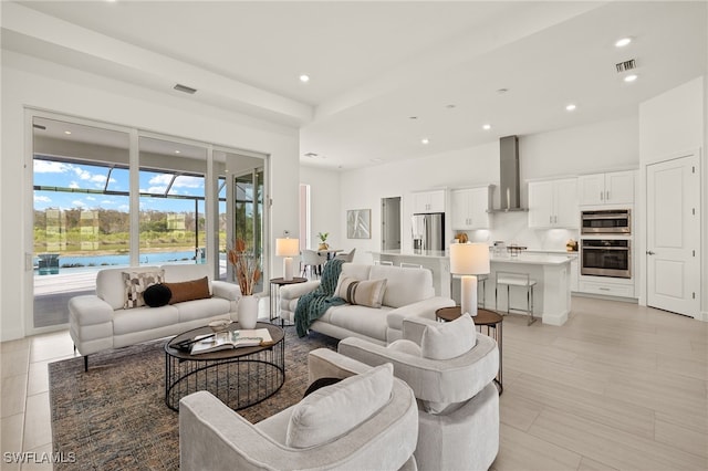 living room with a high ceiling, visible vents, and recessed lighting