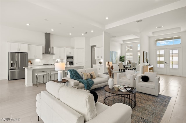 living area with a towering ceiling, visible vents, french doors, and recessed lighting