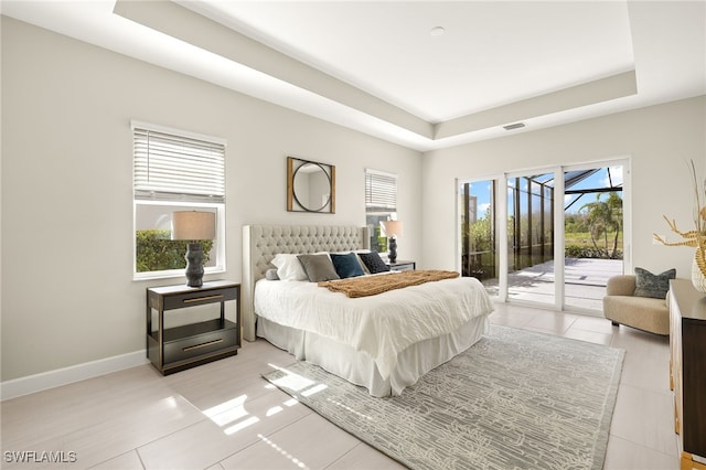 bedroom with access to outside, a tray ceiling, visible vents, and baseboards