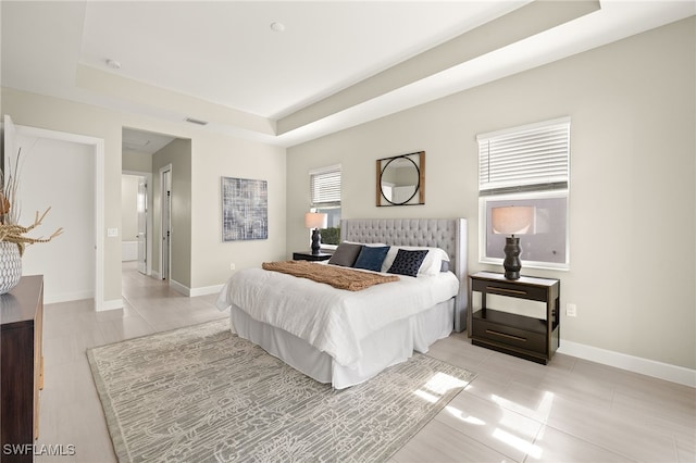 bedroom featuring light tile patterned floors, a tray ceiling, visible vents, and baseboards