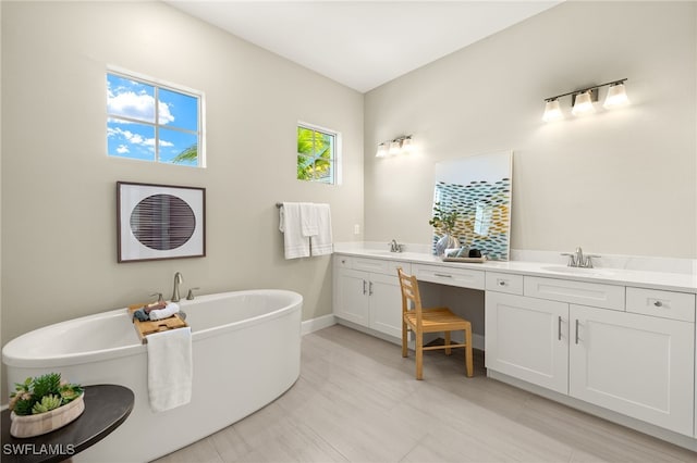 full bath with double vanity, a freestanding bath, baseboards, and a sink