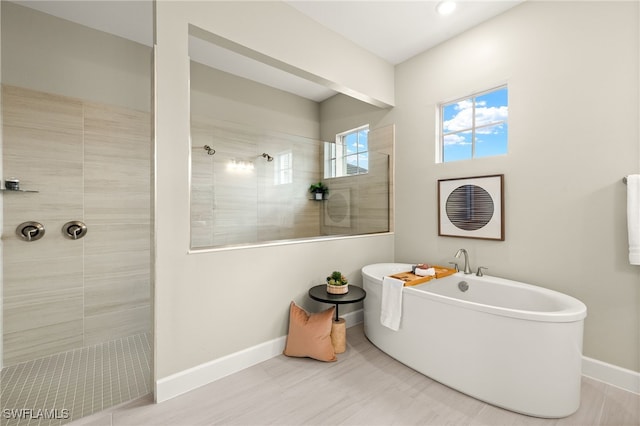 full bath featuring a freestanding tub, baseboards, and walk in shower