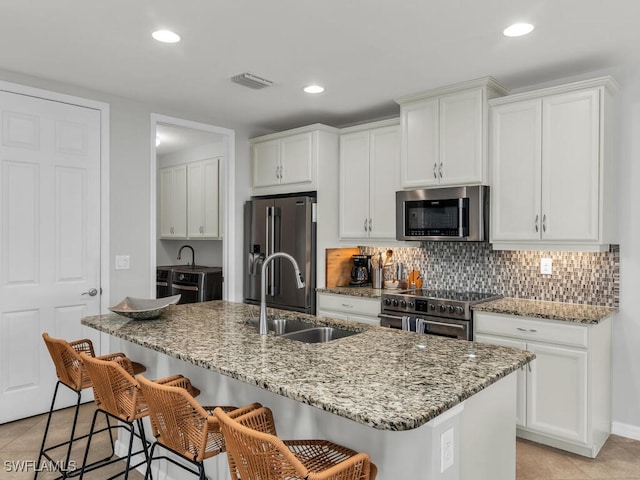 kitchen featuring white cabinets, appliances with stainless steel finishes, and a center island with sink