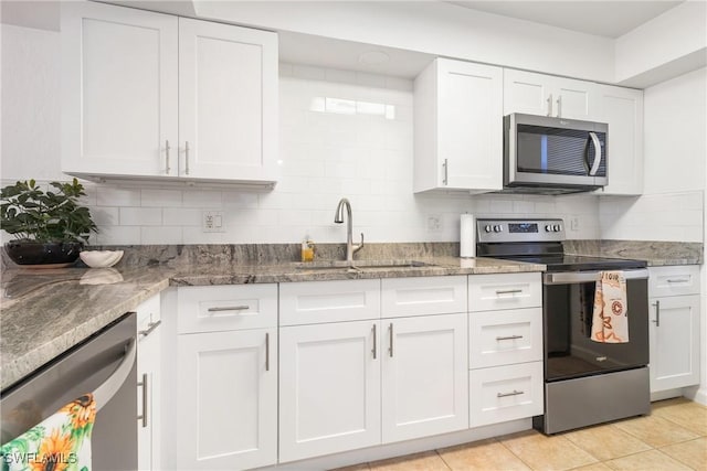 kitchen featuring white cabinets, stainless steel appliances, dark stone counters, and sink