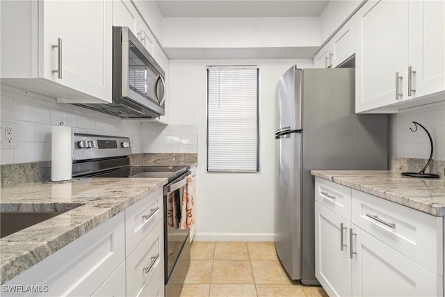 kitchen with backsplash, light stone counters, white cabinetry, and stainless steel appliances