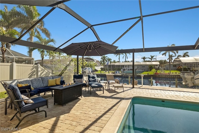 view of patio featuring a lanai, a water view, and an outdoor living space with a fire pit