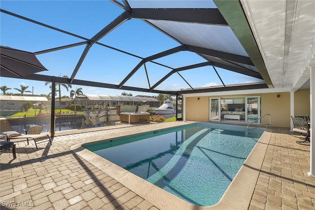 view of swimming pool featuring glass enclosure, a patio area, and a water view