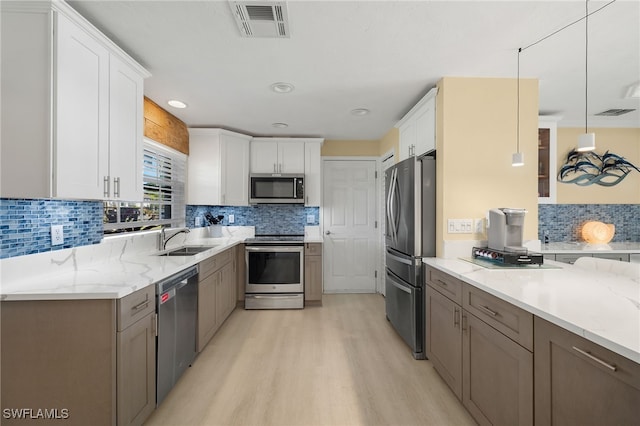 kitchen with white cabinetry, sink, tasteful backsplash, decorative light fixtures, and appliances with stainless steel finishes