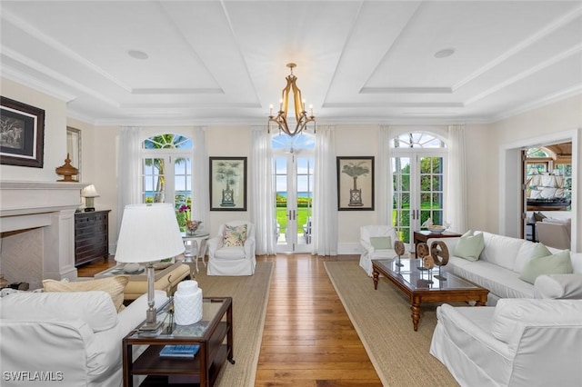 living room featuring an inviting chandelier, a raised ceiling, light wood-type flooring, and french doors