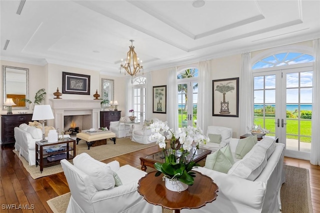 living room with french doors, an inviting chandelier, a raised ceiling, dark hardwood / wood-style floors, and ornamental molding