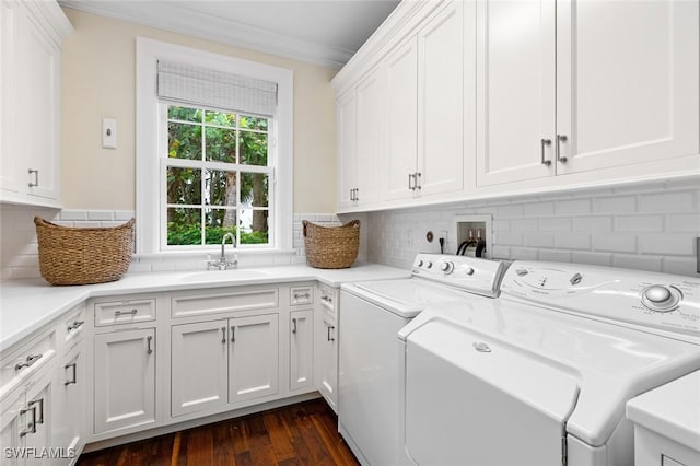 laundry room with dark wood-type flooring, washer and clothes dryer, ornamental molding, sink, and cabinets