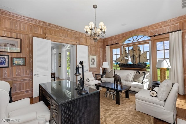 living room with wood walls, light hardwood / wood-style floors, and a notable chandelier