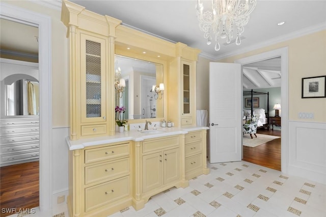 bathroom with hardwood / wood-style flooring, vanity, a notable chandelier, and ornamental molding