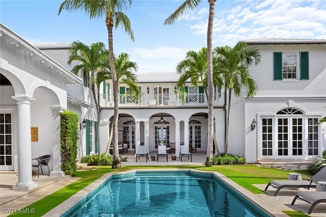 rear view of property featuring french doors, a patio, and a balcony