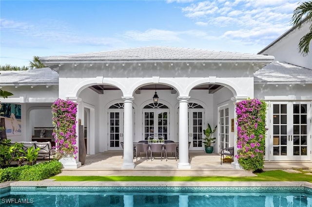 rear view of house with a fireplace, french doors, and a patio area