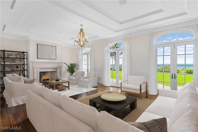 living room featuring french doors, crown molding, a raised ceiling, and wood-type flooring