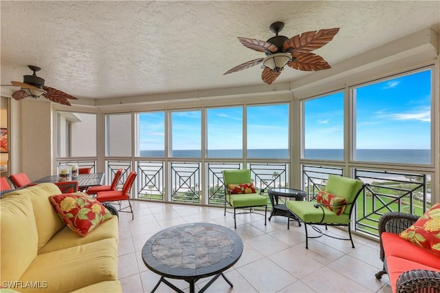 sunroom featuring ceiling fan and a water view