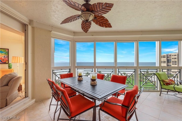 sunroom featuring ceiling fan, a healthy amount of sunlight, and a water view