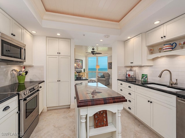 kitchen with a raised ceiling, white cabinets, and stainless steel appliances