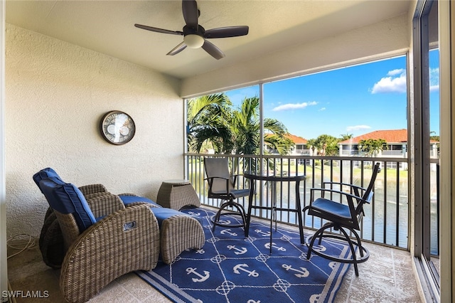 sunroom / solarium featuring a water view and ceiling fan