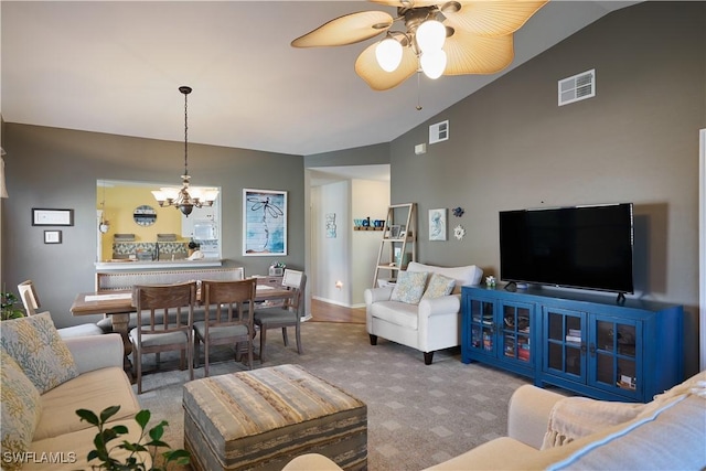 carpeted living room with ceiling fan with notable chandelier and vaulted ceiling