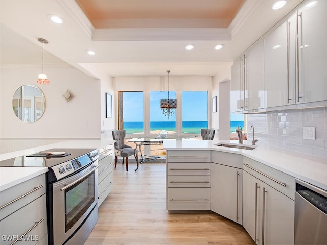 kitchen with white cabinets, a water view, hanging light fixtures, sink, and appliances with stainless steel finishes