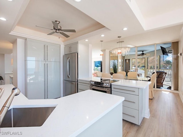 kitchen featuring pendant lighting, sink, appliances with stainless steel finishes, and a tray ceiling