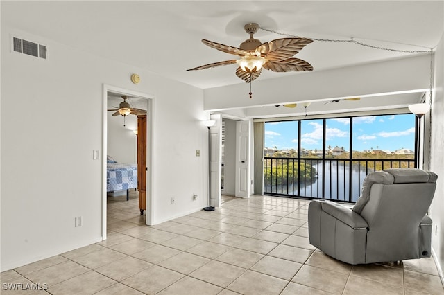 unfurnished living room featuring light tile patterned floors, a water view, and ceiling fan