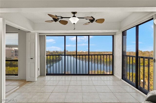 unfurnished sunroom with ceiling fan, plenty of natural light, and a water view