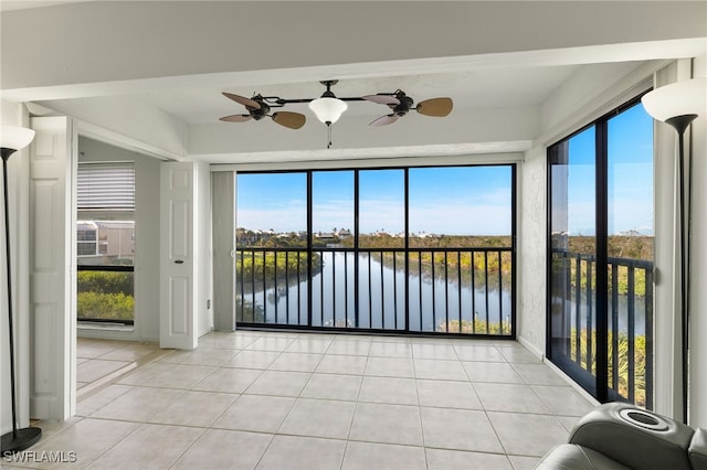 unfurnished sunroom featuring ceiling fan, a healthy amount of sunlight, and a water view