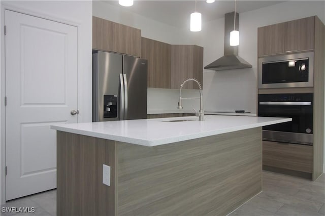 kitchen with stainless steel fridge with ice dispenser, an island with sink, decorative light fixtures, and wall chimney range hood