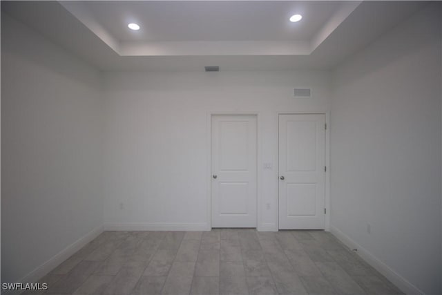 unfurnished bedroom with a tray ceiling and light hardwood / wood-style flooring