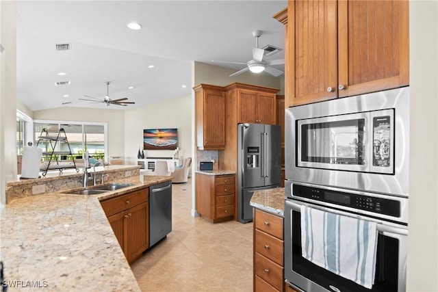 kitchen with light stone counters, stainless steel appliances, ceiling fan, sink, and lofted ceiling