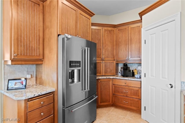 kitchen featuring tasteful backsplash, high end refrigerator, light tile patterned floors, and light stone countertops