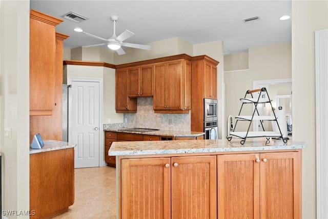 kitchen featuring kitchen peninsula, appliances with stainless steel finishes, tasteful backsplash, light stone counters, and ceiling fan