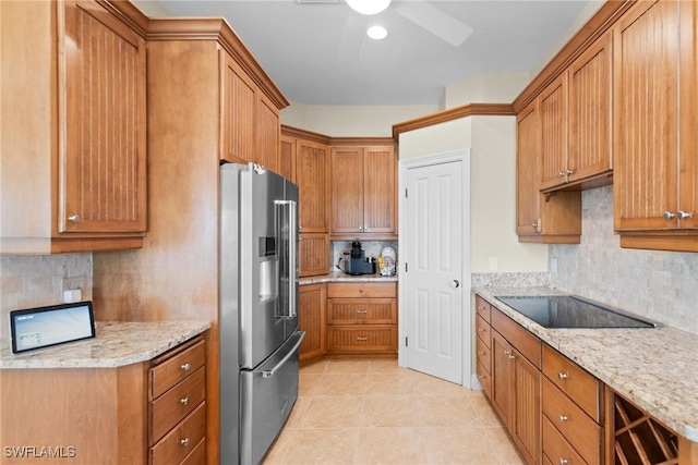 kitchen with black electric stovetop, backsplash, light stone counters, and high end fridge