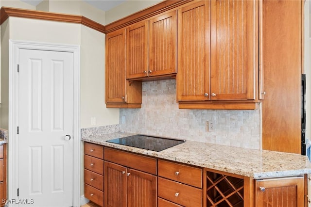 kitchen with decorative backsplash, black electric cooktop, and light stone countertops